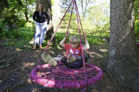 Holly Christensen, left, watches her daughter, Lyra, twirl in a swing, Thursday, May 13, 2021, in Akron, Ohio. Anti-abortion activists say 2021 has been a breakthrough year for legislation in several states seeking to prohibit abortions based on a prenatal diagnosis of Down syndrome. Opponents of the bills, including some parents with children who have Down syndrome like Holly, argue that elected officials should not be meddling with a woman’s deeply personal decision on whether to carry a pregnancy to term after a Down syndrome diagnosis. (AP Photo/Tony Dejak)