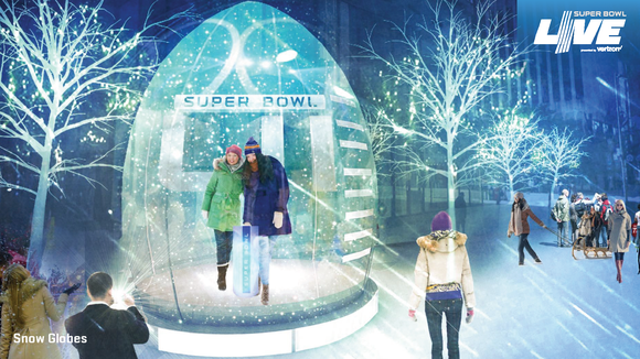 Two fans pose in a mock-up of a snow globe in downtown Minneapolis