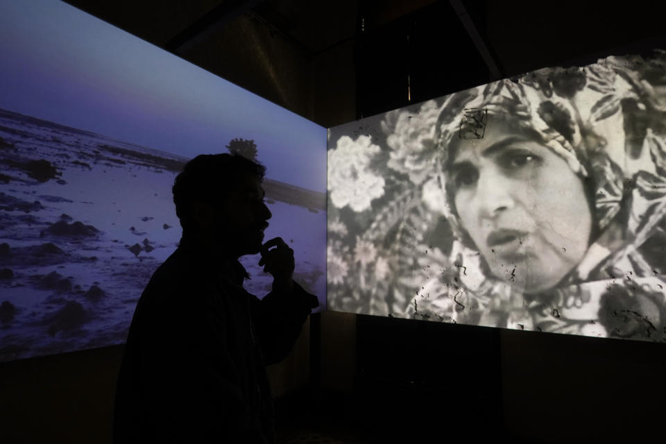 Movie director Majid Al-Remaihi is silhouetted in front of his movie "And Then They Burn the Sea," as he talks to The Associated Press at the exhibition, "Your Ghosts are Mine," during the 60th Biennale of Arts exhibition in Venice, Italy, Tuesday, April 16, 2024. The Venice Biennale contemporary art exhibition opens Saturday for its six-month run through Nov. 26. (AP Photo/Luca Bruno)