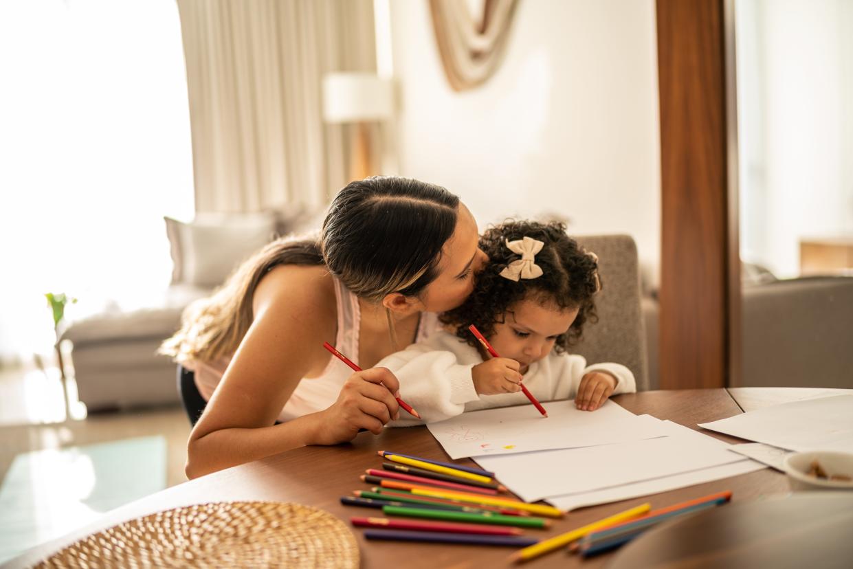 Mother helping her daughter to draw at home