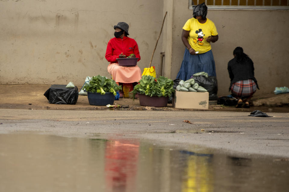 Street vendors wearing masks to help protect themselves from the coronavirus sell vegetables on a pavement in Thokoza, east of Johannesburg, South Africa, Thursday, Jan. 14, 2021. South Africa is struggling to cope with a spike in COVID-19 cases that has already overwhelmed some hospitals, as people returning from widespread holiday travel speed the country's more infectious coronavirus variant. (AP Photo/Themba Hadebe)