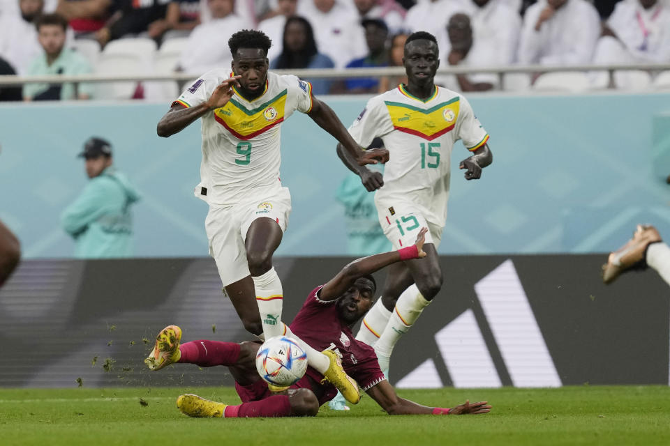 Senegal's Boulaye Dia is tackled by Qatar's Ismail Mohamad during the World Cup group A soccer match between Qatar and Senegal, at the Al Thumama Stadium in Doha, Qatar, Friday, Nov. 25, 2022. (AP Photo/Thanassis Stavrakis)