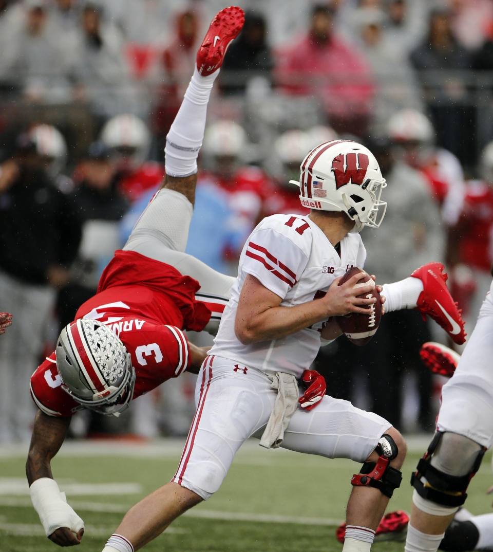 Wisconsin quarterback Jack Coan, right, escapes the grasp of Ohio State defensive back Damon Arnette during the first half of an NCAA college football game Saturday, Oct. 26, 2019, in Columbus, Ohio. (AP Photo/Jay LaPrete)