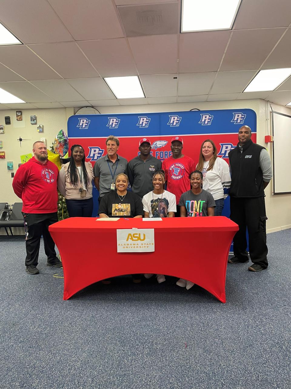 Pine Forest's Autaliah Williams-Gould posing with Eagles coaches and staff at her signing day.