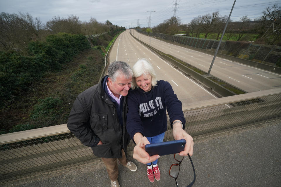 Fiona and Patrick Potter, residents of West Byfleet take a selfie on the Parvis Road bridge in Byfleet, that crosses over a closed section of the M25 between Junctions 10 and 11, while a bridge is demolished and a new gantry is installed. Picture date: Saturday March 16, 2024. (Photo by Yui Mok/PA Images via Getty Images)