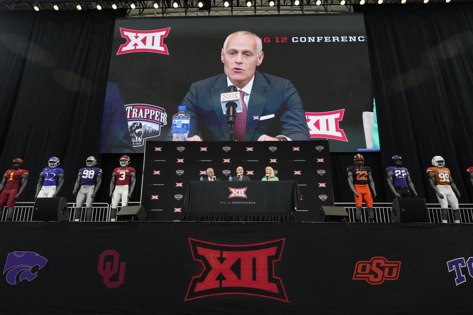 Incoming Big 12 Commissioner Brett Yormark, center, speaks with outgoing Commissioner Bob Bowlsby, left, and Baylor President Linda Livingstone looking on during a news conference opening the NCAA college football Big 12 media days in Arlington, Texas, Wednesday, July 13, 2022. (AP Photo/LM Otero)