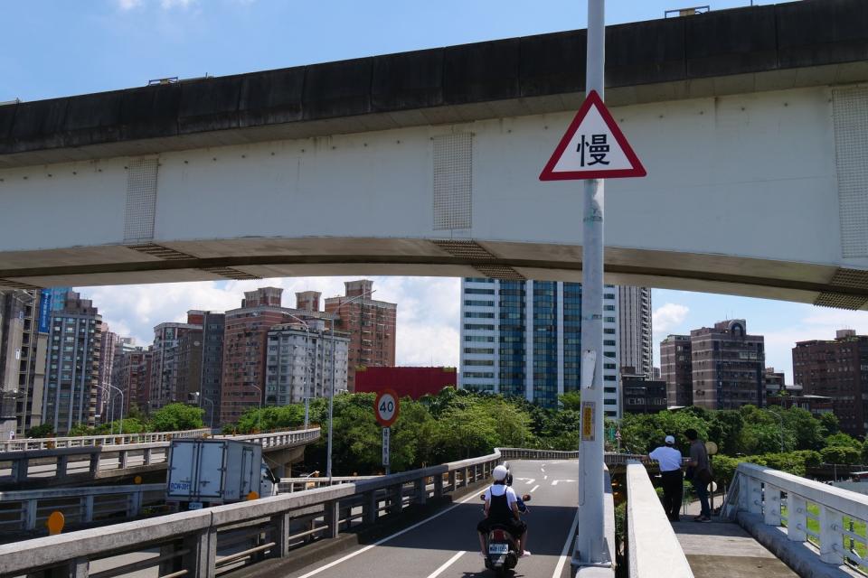 於下橋及彎道處增設「慢」字警示標誌。   圖：新北市交通局提供