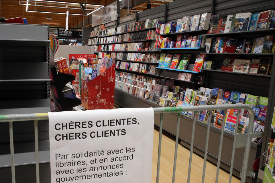 A barrier prevent customers to buy books in a supermarket of Saint Pee sur Nivelle, southwestern France, Tuesday, Nov.3, 2020. French supermarkets are banned from selling flowers and books but they can still sell baby care products, according to a decree published Tuesday laying out new rules for what are considered "essential" items during a monthlong lockdown effort to slow virus infections and save lives. Placard reads: Dear customers, in a s how of solidarity with book stores owners and in accordance with governmental measures.(AP Photo/Bob Edme)