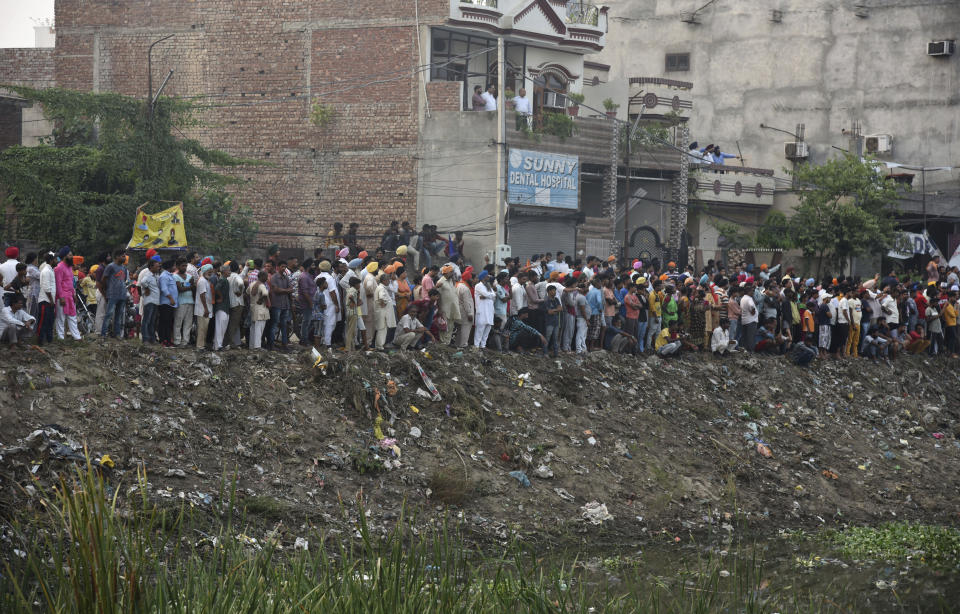 Residents watch rescuers work at the site of an explosion at a fireworks factory in Batala, in the northern Indian state of Punjab, Wednesday, Sept. 4, 2019. More than a dozen people were killed in the explosion that caused the building to catch fire and collapse, officials said. (AP Photo/Prabhjot Gill)