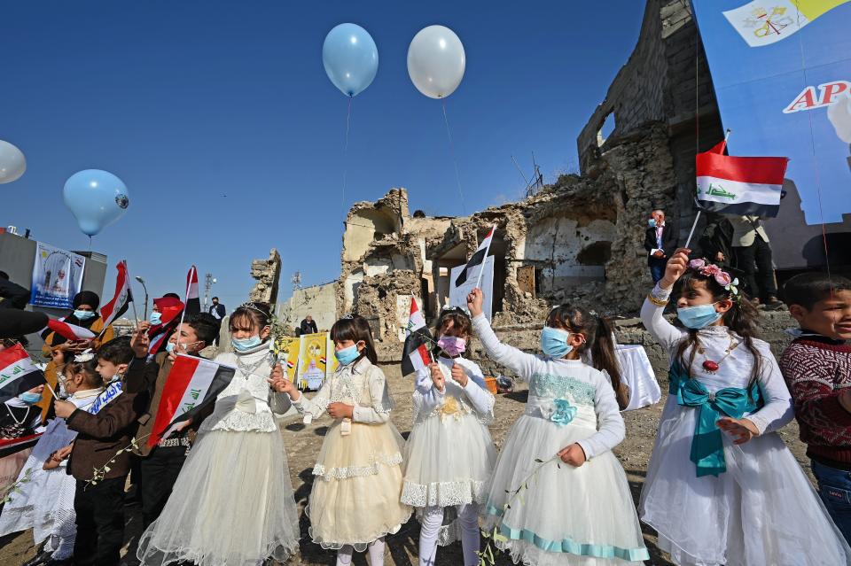 Iraqi children dressed in costumes wave national flags near the ruins of the Syriac Catholic Church of the Immaculate Conception, ahead of the Pope’s visitAFP/Getty