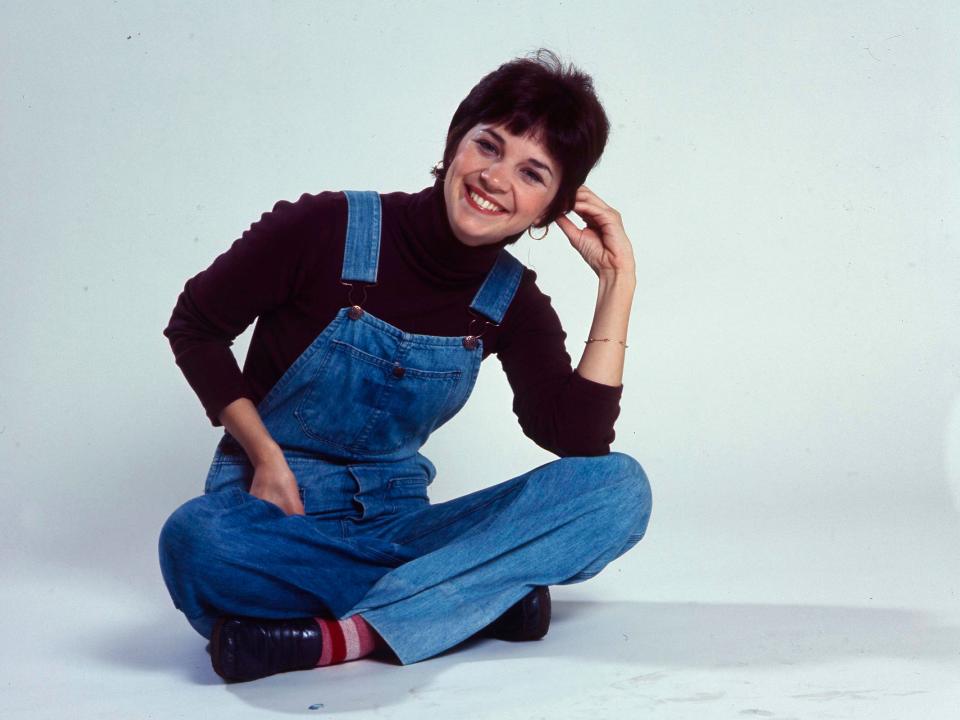 Cindy Williams in overalls sitting down
