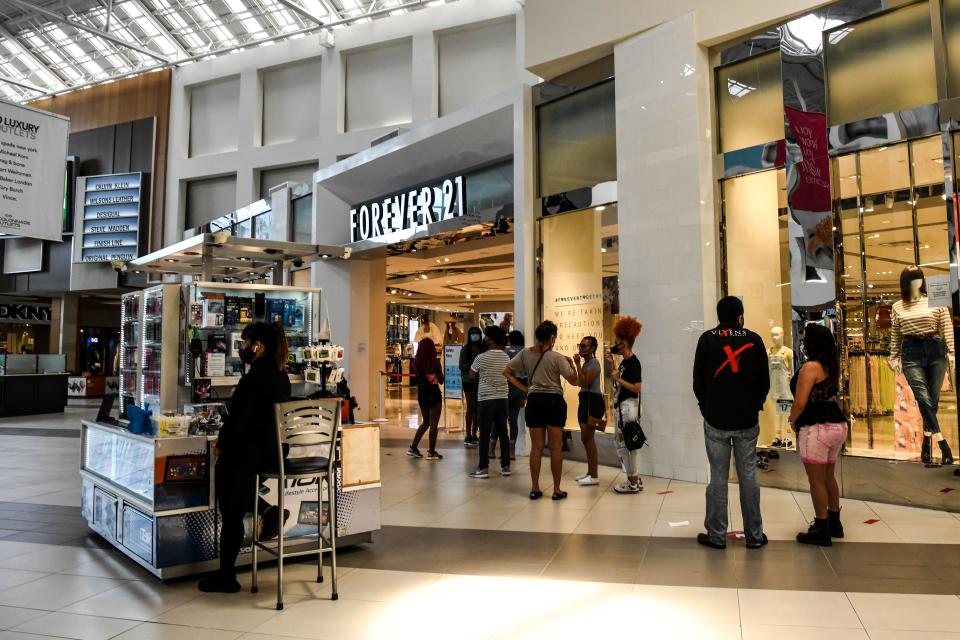 Los clientes hacen cola fuera de la tienda Forever 21 dentro de un centro comercial al oeste de Fort Lauderdale, el 18 de mayo de 2020. El sur de Florida comenzó la reapertura gradual de su economía el 18 de mayo de 2020, retomando las actividades de algunos restaurantes y negocios en Miami y Fort Lauderdale, aunque las playas permanecerán cerradas hasta nuevo aviso. (Foto de CHANDAN KHANNA/AFP vía Getty Images)