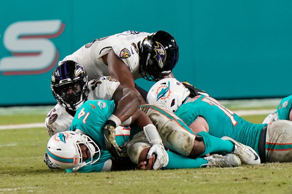 Miami Dolphins quarterback Jacoby Brissett holds his knee after he was sacked by Baltimore Ravens outside linebacker Justin Houston during the second half.