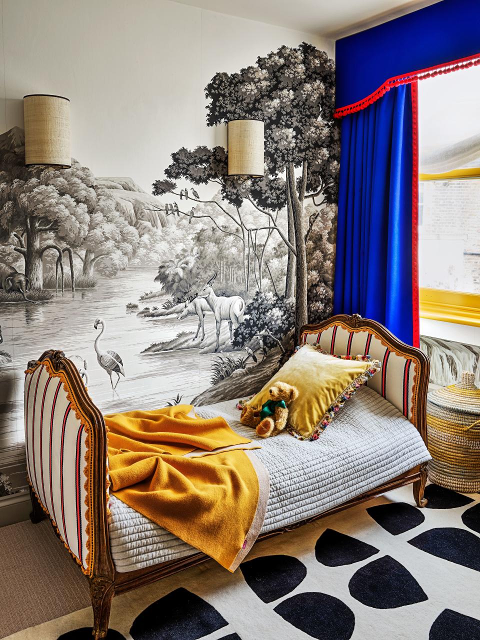 In a child’s bedroom, an 18th-century bed is covered in a Dedar weave. De Gournay wallpaper; custom pelmet and curtains with Samuel & Sons trim; Christopher Farr rug.