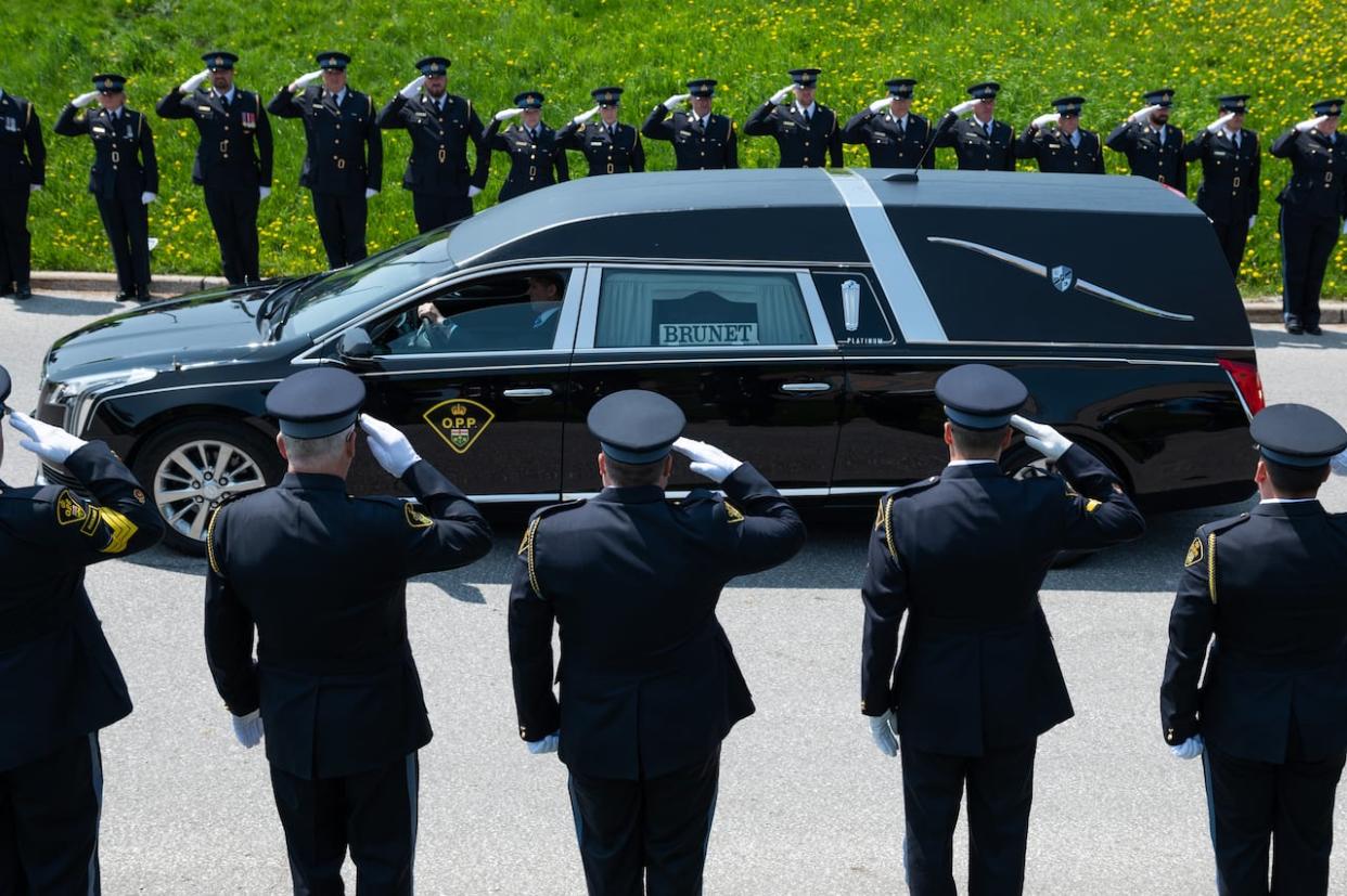 Members of the Ontario Provincial Police salute as the vehicle carrying Sgt. Eric Mueller departs following his funeral. The SIU says no charges are warranted against a surviving officer who shot at the man accused of killing him. (The Canadian Press - image credit)