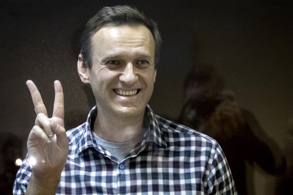 FILE - Russian opposition leader Alexei Navalny gestures as he stands behind a glass panel of a cage in the Babuskinsky District Court in Moscow, Russia, on Feb. 20, 2021. In a span of a decade, Navalny has gone from the Kremlin's biggest foe to Russia's most prominent political prisoner. Already serving two convictions that have landed him in prison for at least nine years, he faces a new trial that could keep him behind for another two decades. (AP Photo/Alexander Zemlianichenko, File)