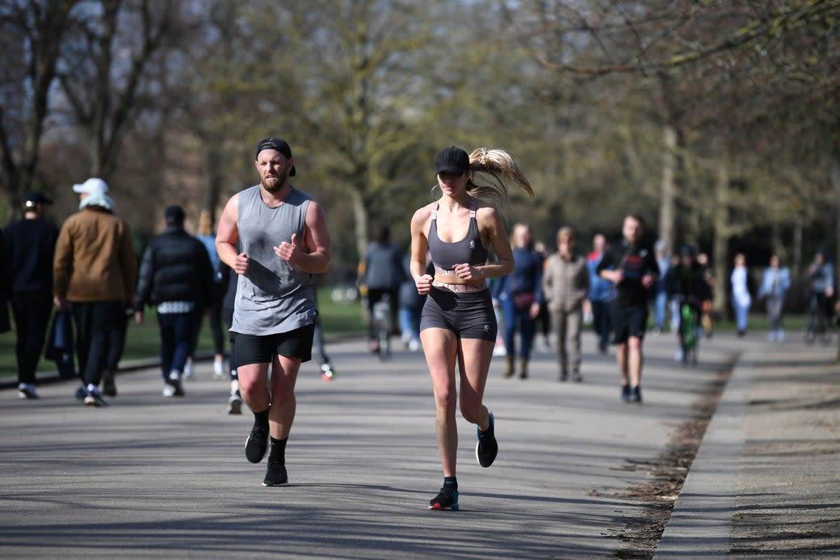 A couple enjoy the winter sunshine as they jog in Victoria Park, east London (Stock image)  (AFP via Getty Images)