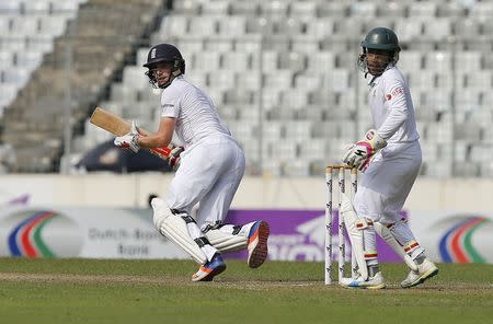 Cricket - Bangladesh v England - Second Test cricket match - Sher-e-Bangla Stadium, Dhaka, Bangladesh - 29/10/16. England's Chris Woakes (L) plays a shot as Bangladesh's captain and wicketkeeper Mushfiqur Rahim looks on. REUTERS/Mohammad Ponir Hossain