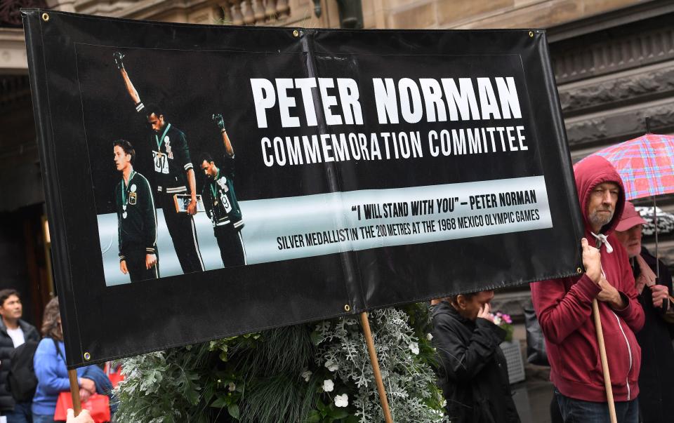 A photo taken in Melbourne on October 9, 2018, shows a man holding a banner commemorating Australian runner Peter Norman