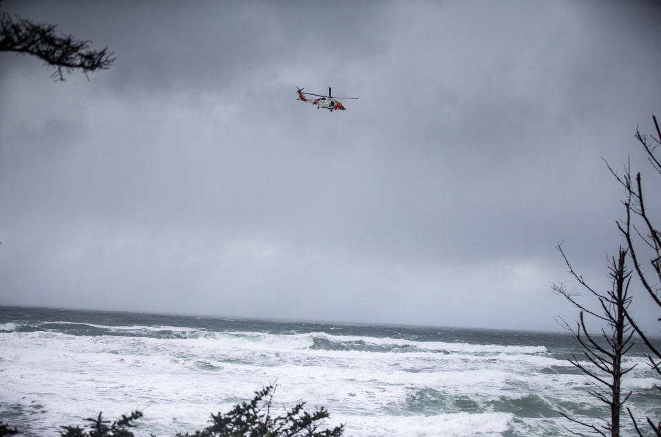 In this Sunday, Jan. 12, 2020 photo, a Coast Guard helicopter continues the search for a missing boy near Falcon Cove Beach in Clastop county, Ore. A 7-year-old girl is dead and her 4-year-old brother is missing after they and their father were swept into the ocean on the Oregon coast amid a high-surf warning. The father was holding the two children when a wave swept all three into the water Saturday, Jan. 11 in the Falcon Cove area, near the small coastal community of Cannon Beach, authorities said. (Mark Graves/The Oregonian via AP)