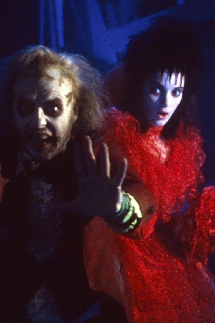 Beetlejuice stands in front of Lydia who is in a large gown