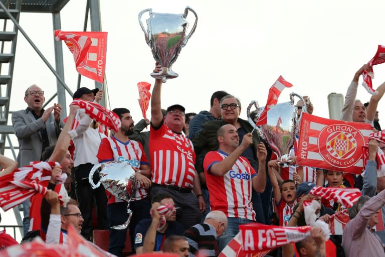 Unos aficionados del Girona sostienen unos globos con la forma del trofeo de la Liga de Campeones durante un partido de la liga española de fútbol contra el visitante FC Barcelona el 4 de mayo de 2024 (Lluís Gené)