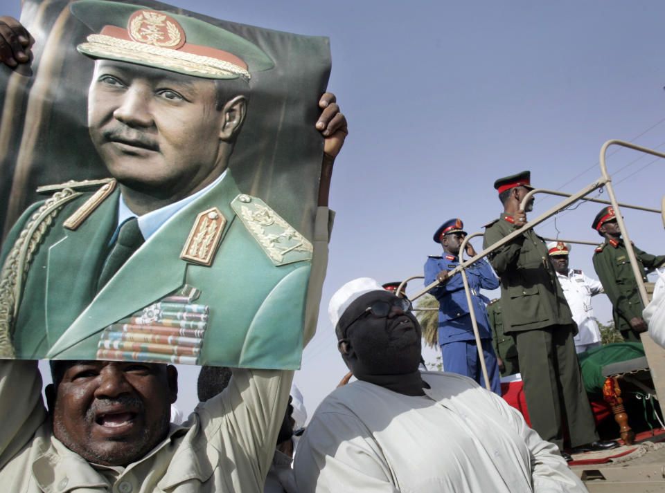 FILE - A Sudanese reacts as he holds a poster showing former Sudanese President Jaafar al-Nimeiri, who became Sudan's president in 1969 and was overthrown in a bloodless coup in 1985, during his military funeral in Omdurman, Khartoum, Sunday, May 31, 2009. (AP Photo/Abd Raouf, File