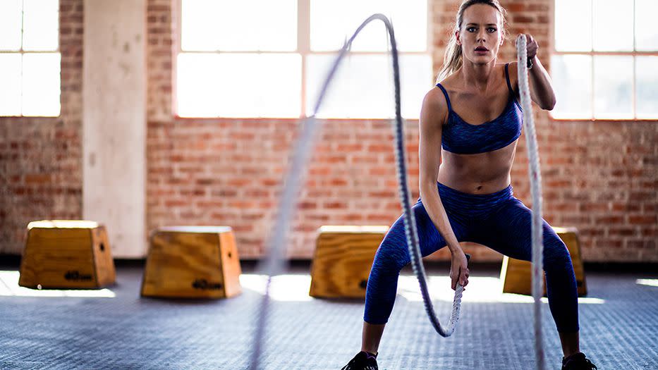 a person exercising with battle ropes in a gym space