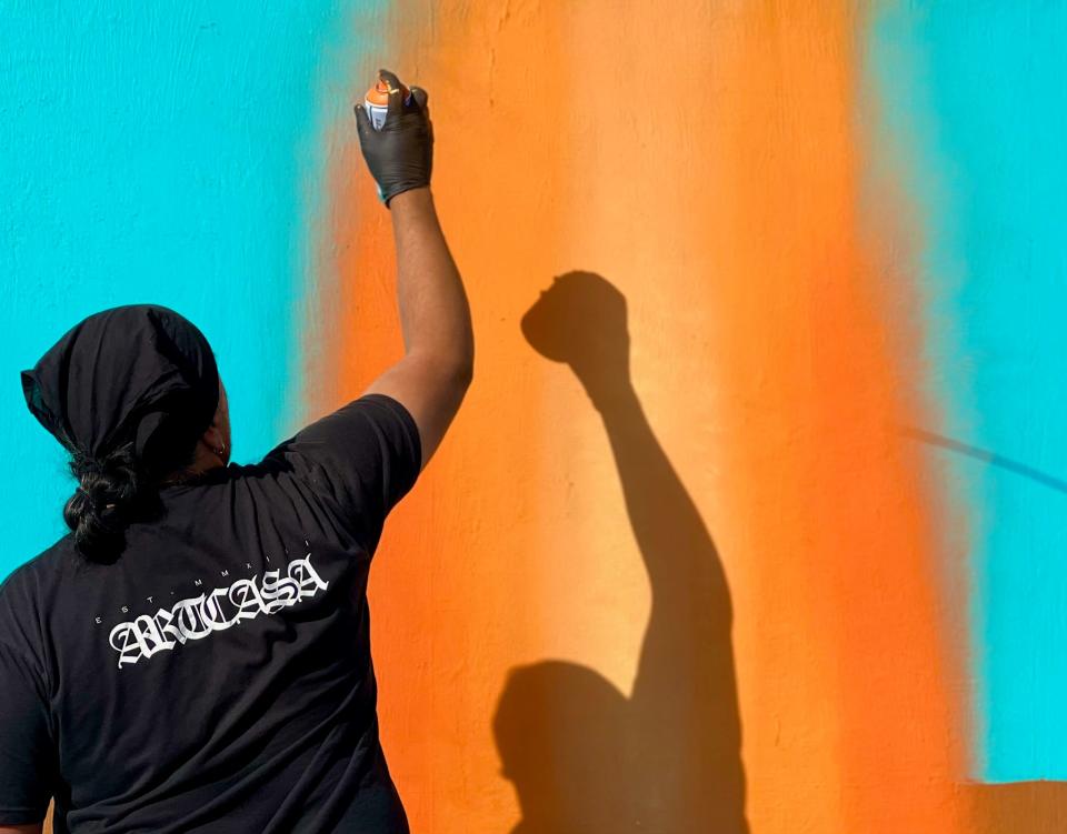 Muralist Thomas “Breeze” Marcus works on his newest mural on the outside of the Fry Bread House in Phoenix.