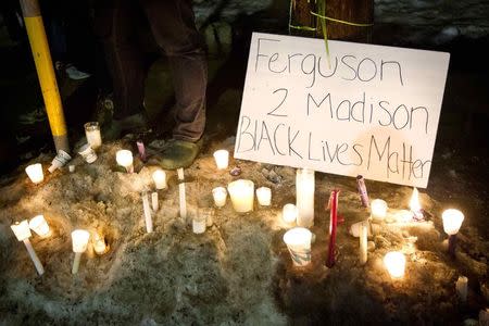 Candles are piled in the snow outside the home of Tony Robinson Jr. during a candlelight vigil on Williamson Street in Madison, Wisconsin March 8, 2015. REUTERS/Ben Brewer