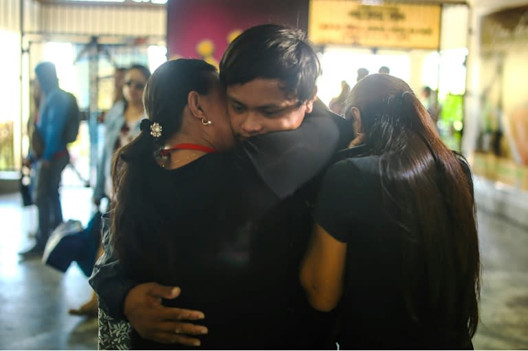 Filipino fisherman Rolando Omongos (C) 21 is hugged by his mother Rosalie (L) and another sibling, shortly after arriving at General Santos City airport