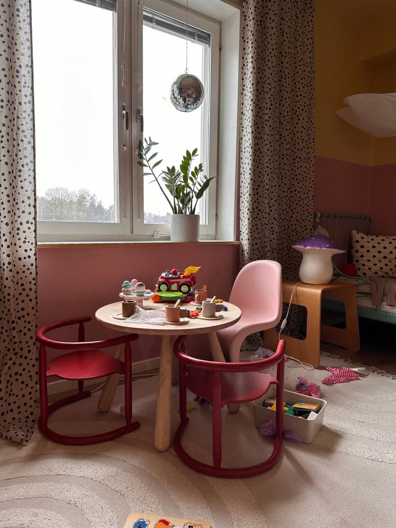 There are red child-sized chairs around a small children's craft table.