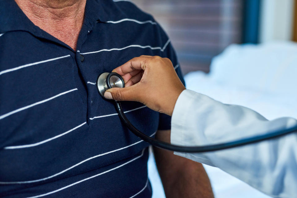 A doctor is using a stethoscope on a patient's chest to listen to the heart