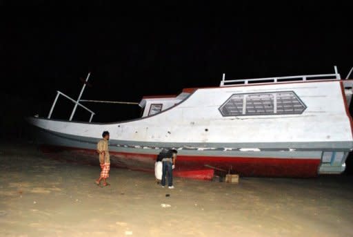 Local residents view an abandoned boat, believed to have been used by Afghan asylum seekers, on the shores of Lombok island, located in eastern Indonesia early on April 14. Indonesian authorities located the missing boat enroute to Australia and said that the dozens of asylum seekers it was carrying were believed to have fled