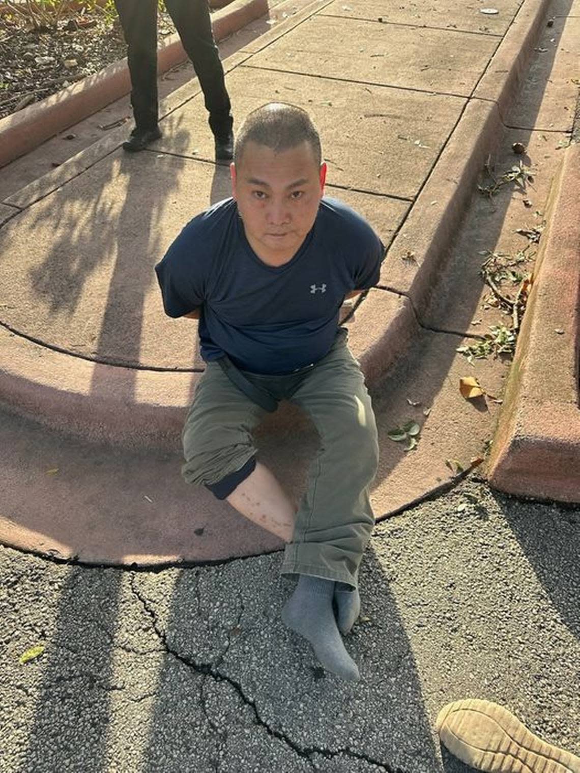 Chen Wu aka Wu Chen in handcuffs on a Miami Beach curb.