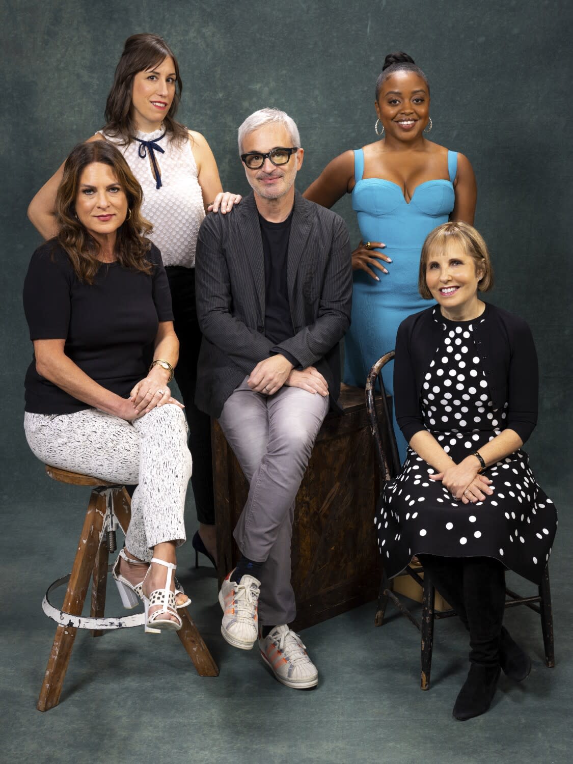 A group of 5 people sit against a backdrop.