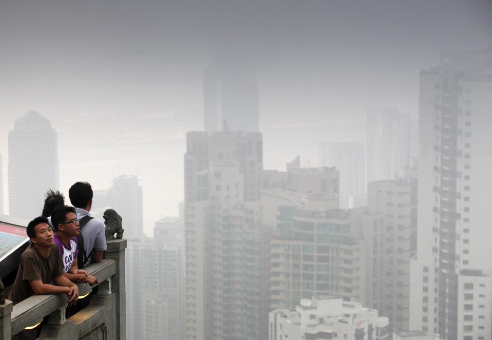 People look across the Hong Kong skyline shrouded by smog.