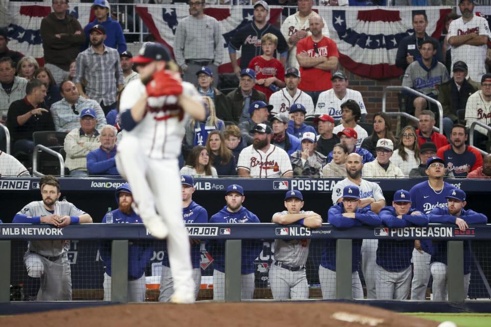 The Los Angeles Dodgers bench watches as Atlanta Braves relief pitcher A.J. Minter delivers a pitch