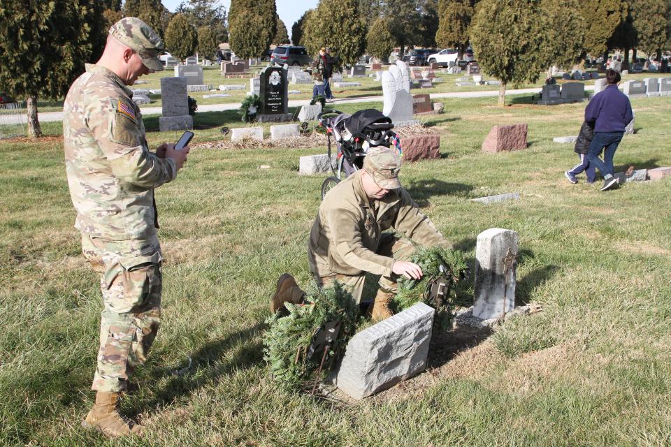 Sgt. Tim Claubaugh of Elmore, and SSG Temos Wooten of Waterville, both members of India Co. RRB, place wreaths on graves at Clay Township Cemetery in Genoa. More than 2,000 wreaths were placed on veterans' graves across Ottawa County on Saturday by military servicemen and volunteers through the Wreaths Across America program.