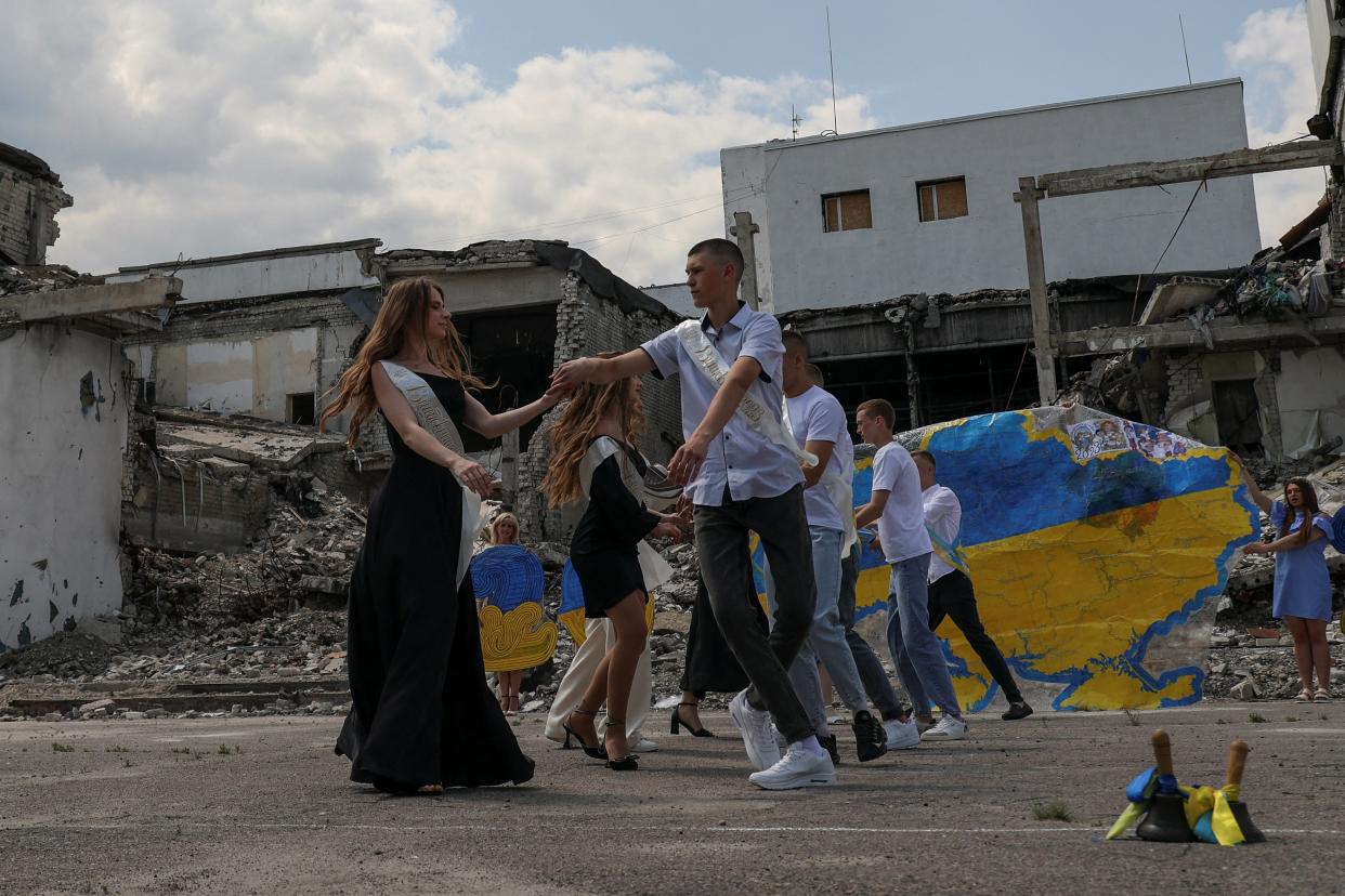 Graduates of a local lyceum dance in front of the local Palace of Culture destroyed by a Russian military strike (REUTERS)
