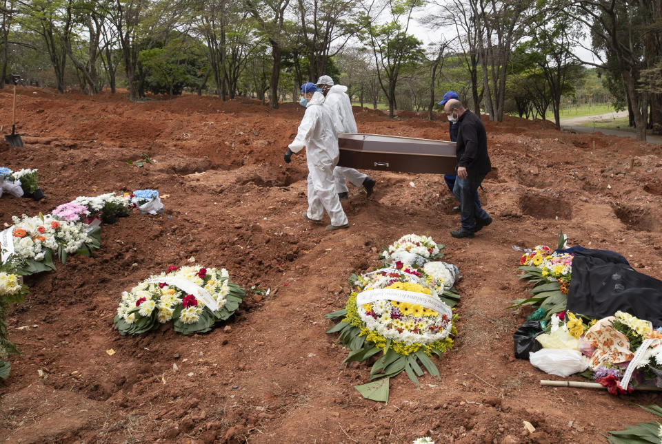 Cemetery workers in protective clothing and nephew Darick Caverni carry the coffin that contain the remains of 88-year-old Wilma Caverni, who died of the new coronavirus, at the Vila Formosa cemetery in Sao Paulo, Brazil, Wednesday, July 15, 2020. Brazil is nearing 2 million cases of COVID-19 and 75,000 deaths. (AP Photo/Andre Penner)