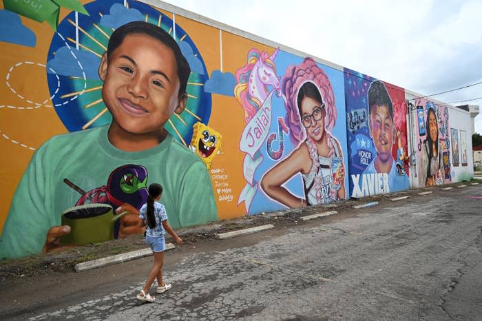 Caitlyne Gonzales walks past murals of students killed in the Uvalde school shooting.