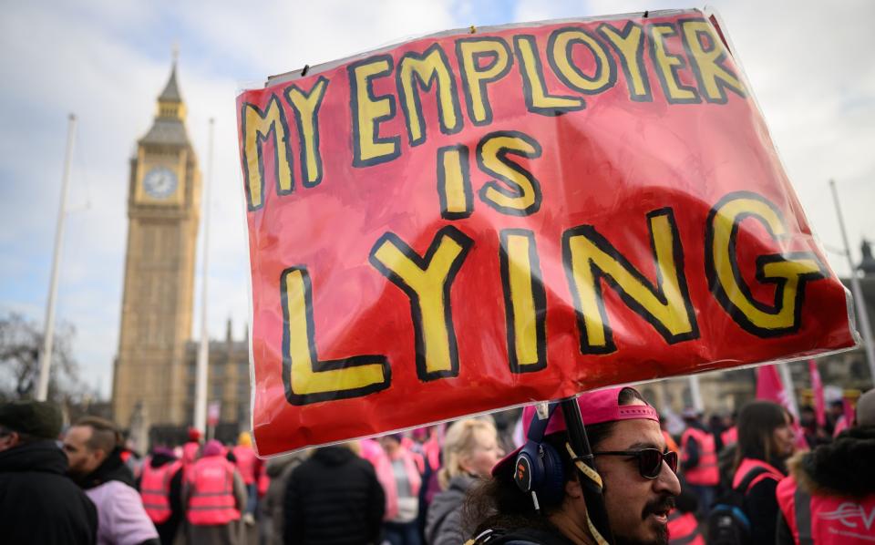 A man holds up a placard as striking mail workers and supporters gather in Parliament Square to listen to speeches by union leaders and representatives on December 9, 2022 - Leon Neal/Getty Images Europe