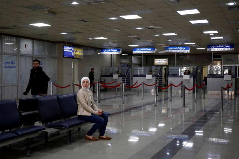 Woman sits inside Aleppo international airport that has been reopened for the first time in years