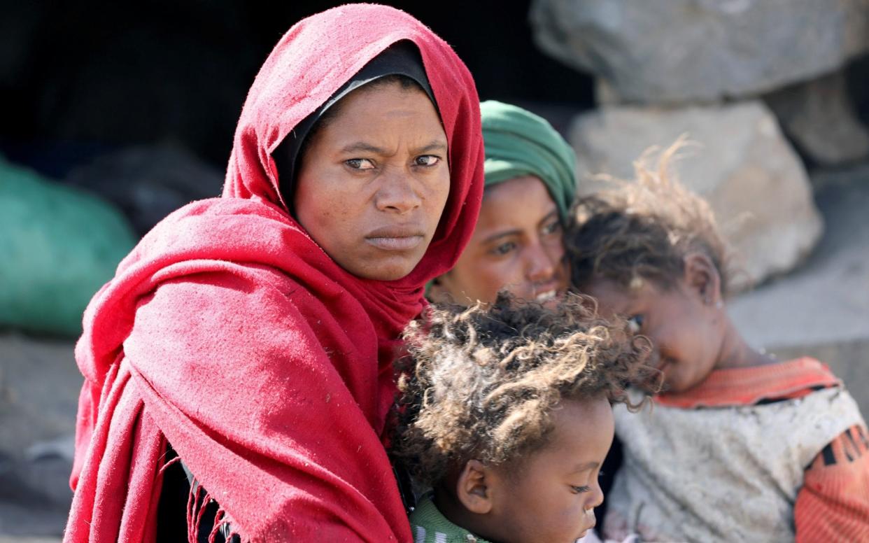 A woman with her children at a camp for internally displaced people on the outskirts of Sanaa, Yemen March 1, 2021 - KHALED ABDULLAH/REUTERS 