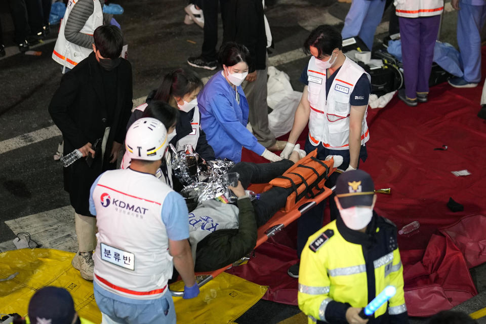 Rescue workers carry injured people on the street near the scene in Seoul, South Korea, Sunday, Oct. 30, 2022. South Korean officials say at least 120 people were killed and 100 more were injured as they were crushed by a large crowd pushing forward on a narrow street during Halloween festivities in the capital of Seoul. Choi Seong-beom, chief of Seoul’s Yongsan fire department, said the death toll could rise, saying that an unspecified number among the injured were in critical conditions. (AP Photo/Lee Jin-man)