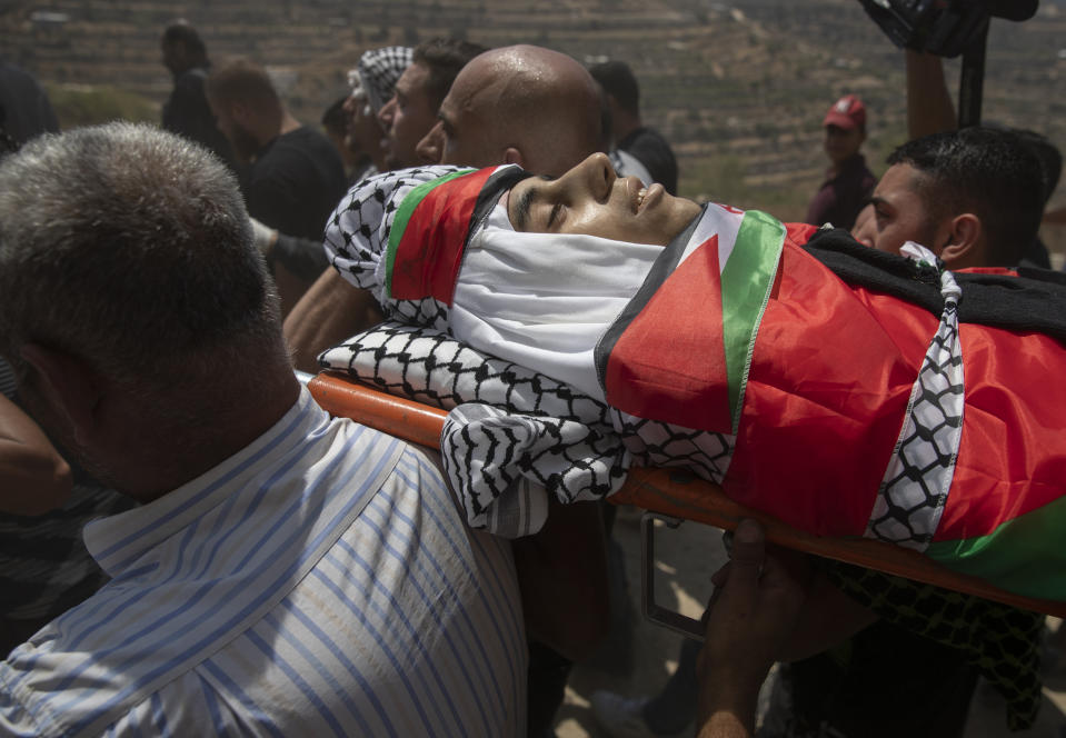 Palestinian mourners carry the body of Shaukat Awad, 20 during his funeral in the West Bank village of Beit Ummar, near Hebron, Friday, July. 30, 2021. Israeli troops shot and killed the 20 year old Palestinian man, Palestinian health officials said, during clashes that erupted in the occupied West Bank following the funeral of a Palestinian boy killed by army fire the previous day. (AP Photo/Nasser Nasser)