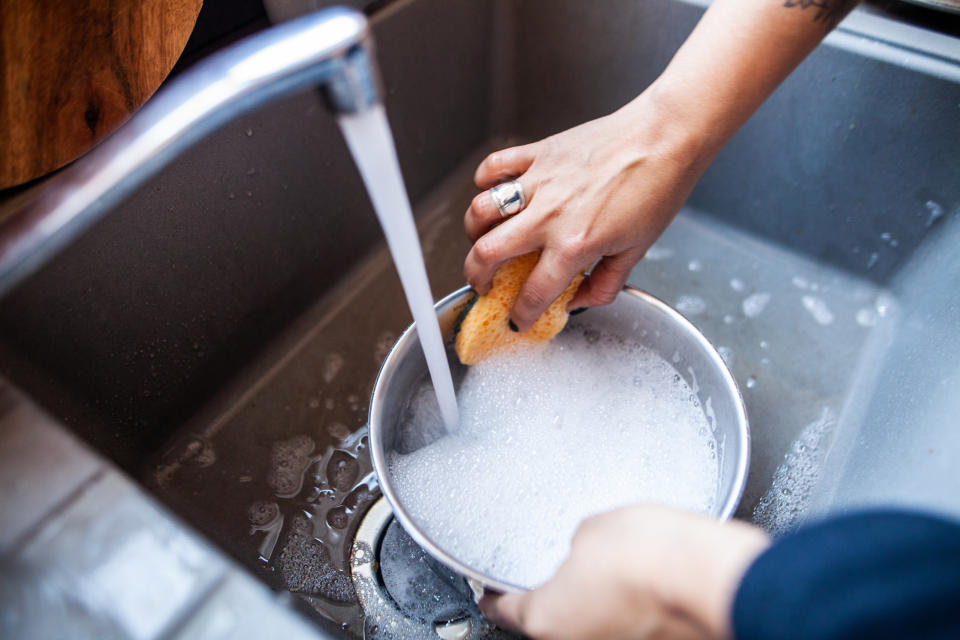 hands washing a soapy bowl in the sink with a sponge