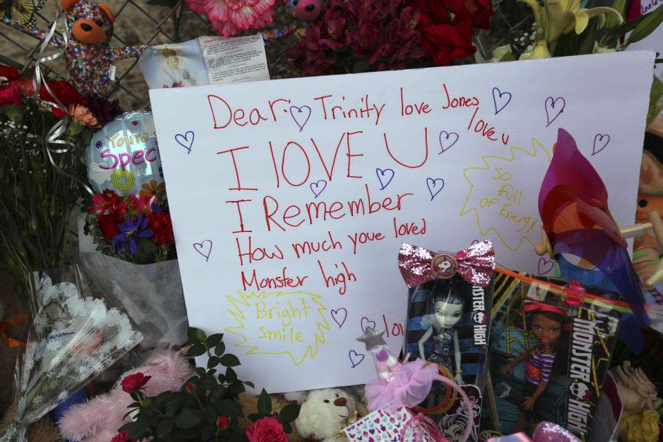 Dozens of tributes are seen at a large memorial to Trinity Love Jones, the 9-year-old girl whose body was found in a duffel bag along a suburban Los Angeles equestrian trail, seen at rear, in Hacienda Heights, Calif., Monday, March 11, 2019. Two people have been detained in connection with the case. The discovery happened last week. (AP Photo/Reed Saxon)