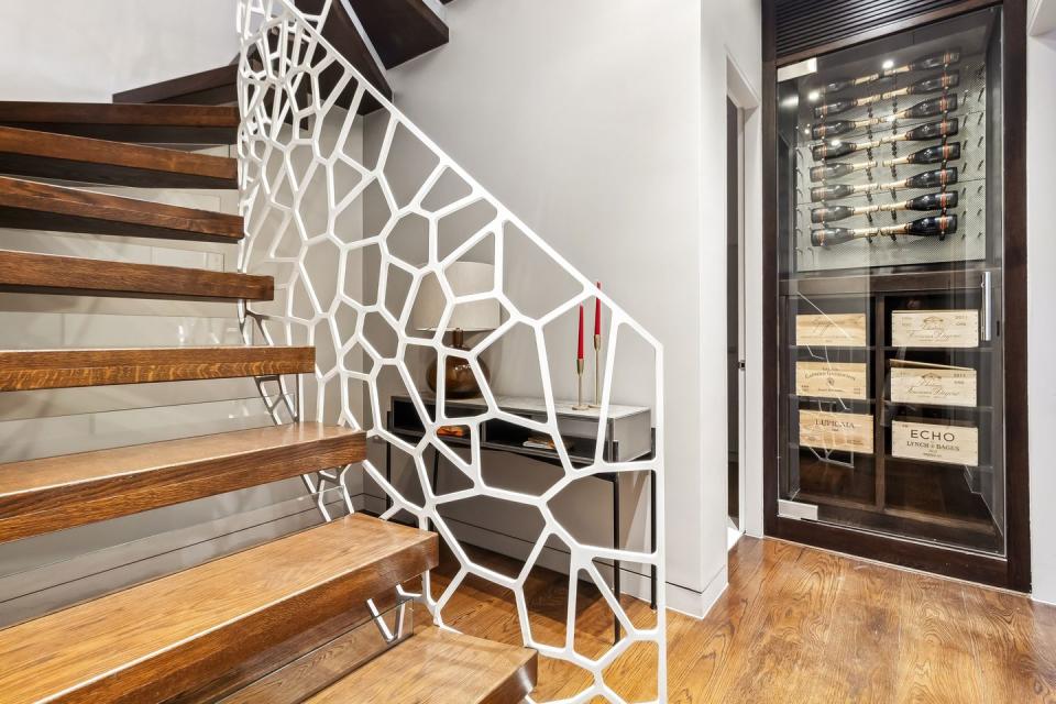 a wooden staircase in denbigh close notting hill home with wine wall at the end of the corridor